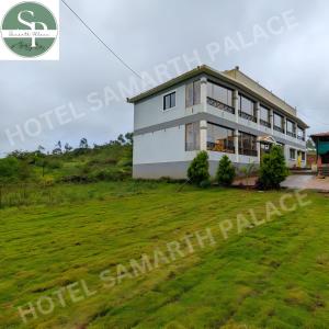 Hotel SAMARTH PALACE في ماهاباليشوار: منزل على تلة مع حقل أخضر