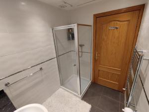 ein Badezimmer mit einer Dusche, einem WC und einer Holztür in der Unterkunft Heather Cottage Luss in Luss