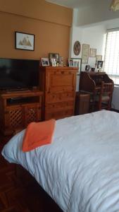 a bedroom with a bed and a dresser and a television at Edificio frente Club Tenis. in Cochabamba