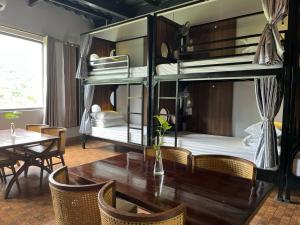 ハザンにあるRocks Ha Giang Hostel & Tourの二段ベッド2台とテーブルが備わる客室です。