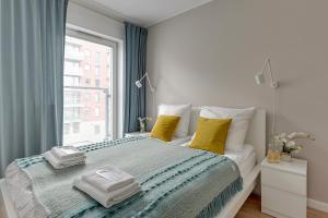 a bedroom with a bed with yellow pillows and a window at Chmielna Park 5 TriApart® in Gdańsk