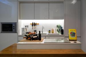 een keuken met witte kasten en een aanrechtblad bij Cristalia,Roof terrace in city center, Garage, Netflix 75inch TV in Funchal +11 foto's