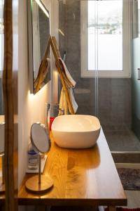 een badkamer met een witte wastafel op een houten aanrecht bij Cristalia,Roof terrace in city center, Garage, Netflix 75inch TV in Funchal