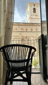un banc assis devant une fenêtre avec une tour d'horloge dans l'établissement Palazzo Tranfo Al Duomo Accommodation, à Tropea