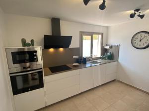 a kitchen with white cabinets and a clock on the wall at Casa Blanca Caleta - Golf & Sea Views - private heated Saltwater Pool - BBQ - Aircondition" in Caleta De Fuste