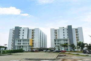 two large white apartment buildings with a parking lot at Barata Hotel Near Bandara Soekarno Hatta in Teko