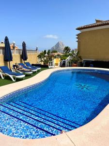 una grande piscina blu con sedie e ombrelloni di Casa Rose - 4-Bed villa with private pool in Calpe a Calpe