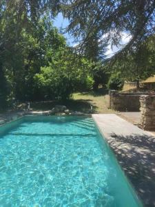 a swimming pool with blue water in a yard at Les Grottes in Sivergues +3 photos