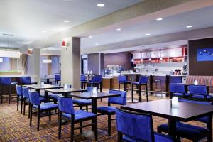 a restaurant with tables and blue chairs and a bar at Courtyard by Marriott Gainesville FL in Gainesville