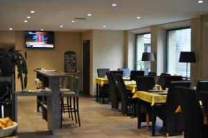 un ristorante con tavoli e sedie e una televisione sul muro di Hôtel Le Loft a Trie sur Baise