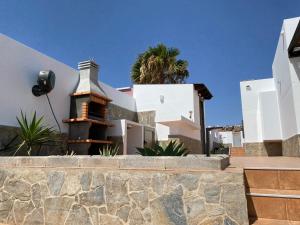 una casa con una pared de piedra delante de ella en CASA BLANCA - Sea Views - Private Pool - WiFi - BBQ, en Caleta de Fuste