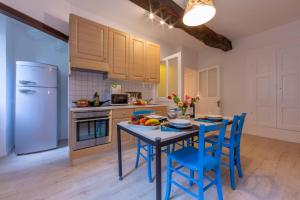 a kitchen with blue chairs and a table with fruit on it at Casa Gialla - Happy Rentals in Pugerna