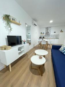 ein weißes Wohnzimmer mit einem blauen Sofa und Tischen in der Unterkunft Blanco y Añil Plaza in Valdepeñas