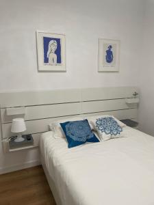 ein weißes Bett mit zwei blauen Kissen in einem Schlafzimmer in der Unterkunft Blanco y Añil Plaza in Valdepeñas