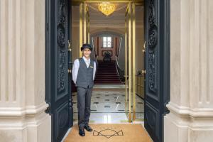 Um homem de fato e chapéu parado num corredor em MS Collection Aveiro - Palacete Valdemouro em Aveiro