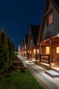 a row of wooden buildings at night at Rega domki in Sarbinowo