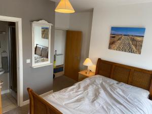 a bedroom with a white bed and a mirror at City centre Rooftop apartment alongside river Suir in Waterford