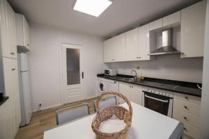 a kitchen with white cabinets and a basket on a table at Villa Anievas in Boó de Piélagos