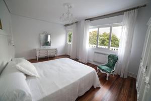 a bedroom with a bed and a chair and windows at Villa Anievas in Boó de Piélagos