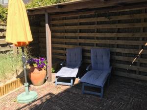 zwei Stühle und ein Regenschirm auf einer Terrasse in der Unterkunft Appartementen de Strandloper in Bergen aan Zee