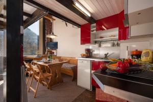 cocina con armarios rojos y mesa de comedor en Résidence Grand Roc - Bruyères 09 - Happy Rentals en Chamonix-Mont-Blanc