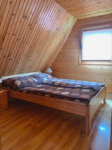 a bed in a log cabin with a window at Rega domki in Sarbinowo