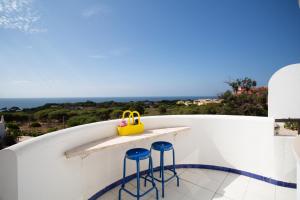 een klein balkon met blauwe krukken en een gele tas bij Coral By Albufeira Rental in Albufeira