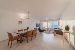 - une salle à manger et un salon avec une table et des chaises dans l'établissement Beachfront apartment with breathtaking sea view, à Netanya
