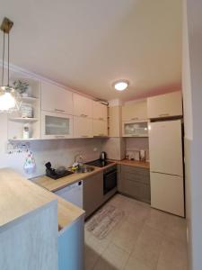 a kitchen with white cabinets and a white refrigerator at VUCETIC Apartment- Podgorica in Podgorica
