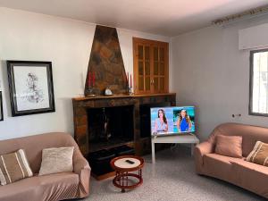 uma sala de estar com dois sofás e uma televisão em Villa con piscina y jardines privados em Bullas