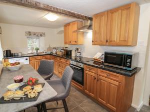 una cocina con armarios de madera y una mesa con comida. en Grove Cottage, en Leominster