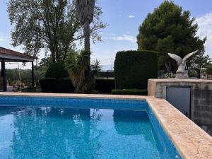 a blue swimming pool with a statue in a yard at Villa con piscina y jardines privados in Bullas