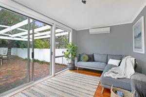 een woonkamer met een bank en een patio bij Hideaway Cottage - Your Southern Highlands Escape in Moss Vale