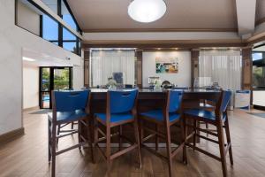 uma cozinha com um grande bar de madeira com cadeiras azuis em Best Western Hampton Coliseum Inn em Hampton