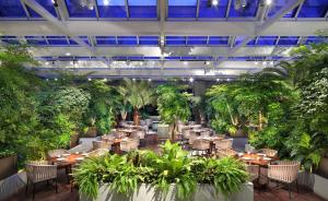 a restaurant with tables and chairs and plants at Hyatt Regency Tianjin East in Tianjin