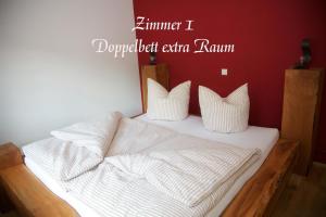een bed met witte lakens en kussens in een kamer bij Alte Kass in Neidlingen