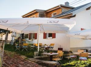 eine Terrasse mit Tischen und Stühlen unter weißen Sonnenschirmen in der Unterkunft Alte Kass in Neidlingen