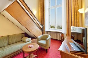 a living room with a couch and a window at Austria Trend Hotel Schloss Wilhelminenberg Wien in Vienna