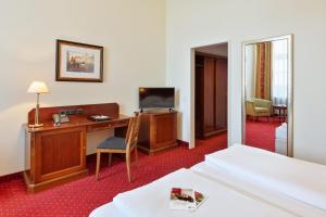 ein Hotelzimmer mit einem Bett, einem Schreibtisch und einem TV in der Unterkunft Austria Trend Hotel Schloss Wilhelminenberg Wien in Wien