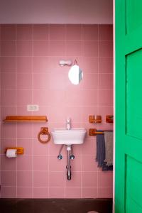 a pink bathroom with a sink and a green door at Hektor in Teguise