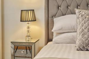 a bed with a side table with a lamp on it at Deluxe River View Apt & Free Parking! in Leeds