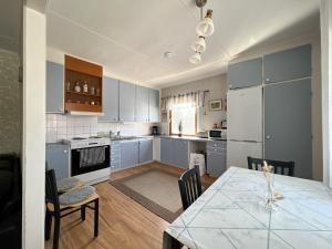 uma cozinha com armários azuis e uma mesa com cadeiras em Långträsk Apartments Villa em Långträsk