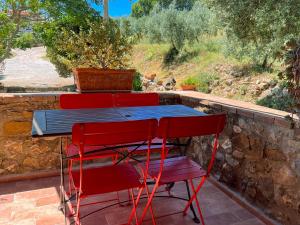 4 rote Stühle und ein blauer Tisch auf einer Terrasse in der Unterkunft Agriturismo Schiaccia Ghiande in Massa Marittima