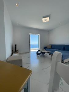 a living room with a blue couch and a table at Endless blue Apartments in Dhërmi