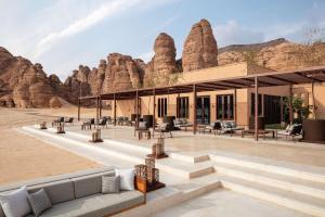 a building with chairs and tables in front of rock formations at Banyan Tree AlUla in Al-ʿUla