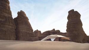 a tent in the middle of a desert with rock formations at Banyan Tree AlUla in Al-ʿUla