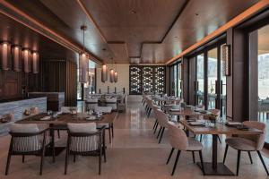 a restaurant with wooden tables and chairs and windows at Banyan Tree AlUla in Al-ʿUla