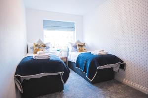 a bedroom with two beds and a window at Luxury 4 Bed, 3 Bathroom, Pet Friendly Villa, Sleeps 8, with Hot Tub in Trearddur Bay in Trearddur