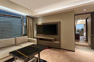 a living room with a couch and a flat screen tv at Sheraton Grand Bengaluru Whitefield Hotel & Convention Center in Bangalore
