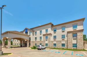 a hotel with a car parked in a parking lot at Baymont Inn & Suites by Wyndham Glen Rose in Glen Rose